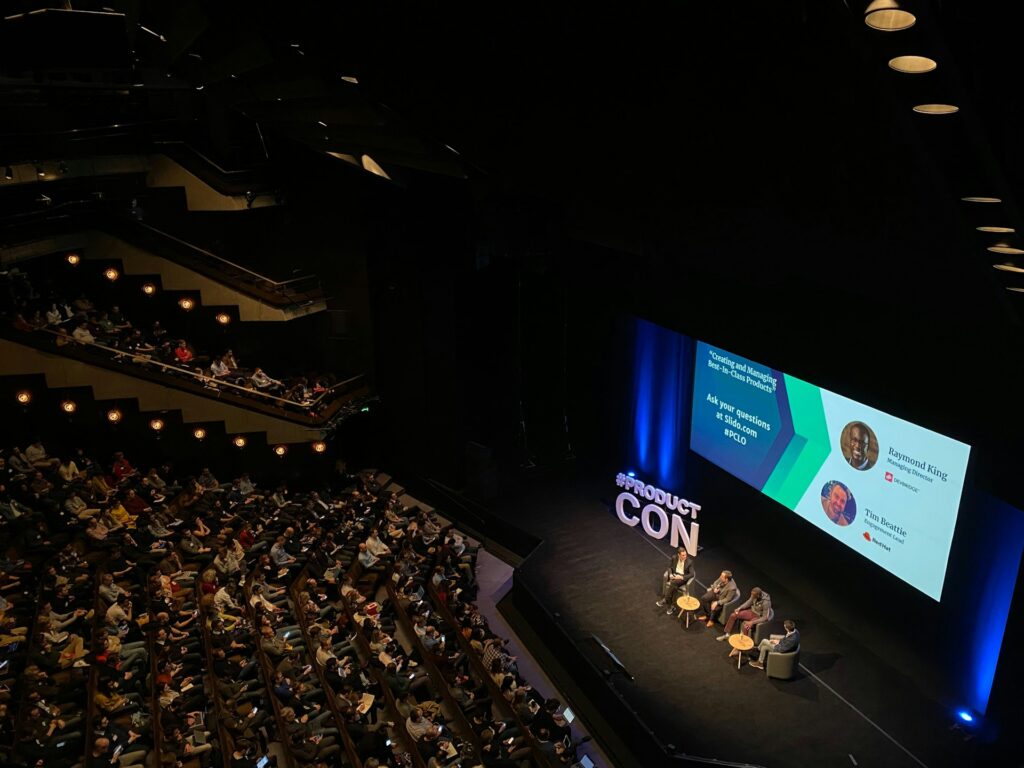 Panel discussion on stage with multiple speakers and audience, showcasing a professional visual setup for a panel discussion