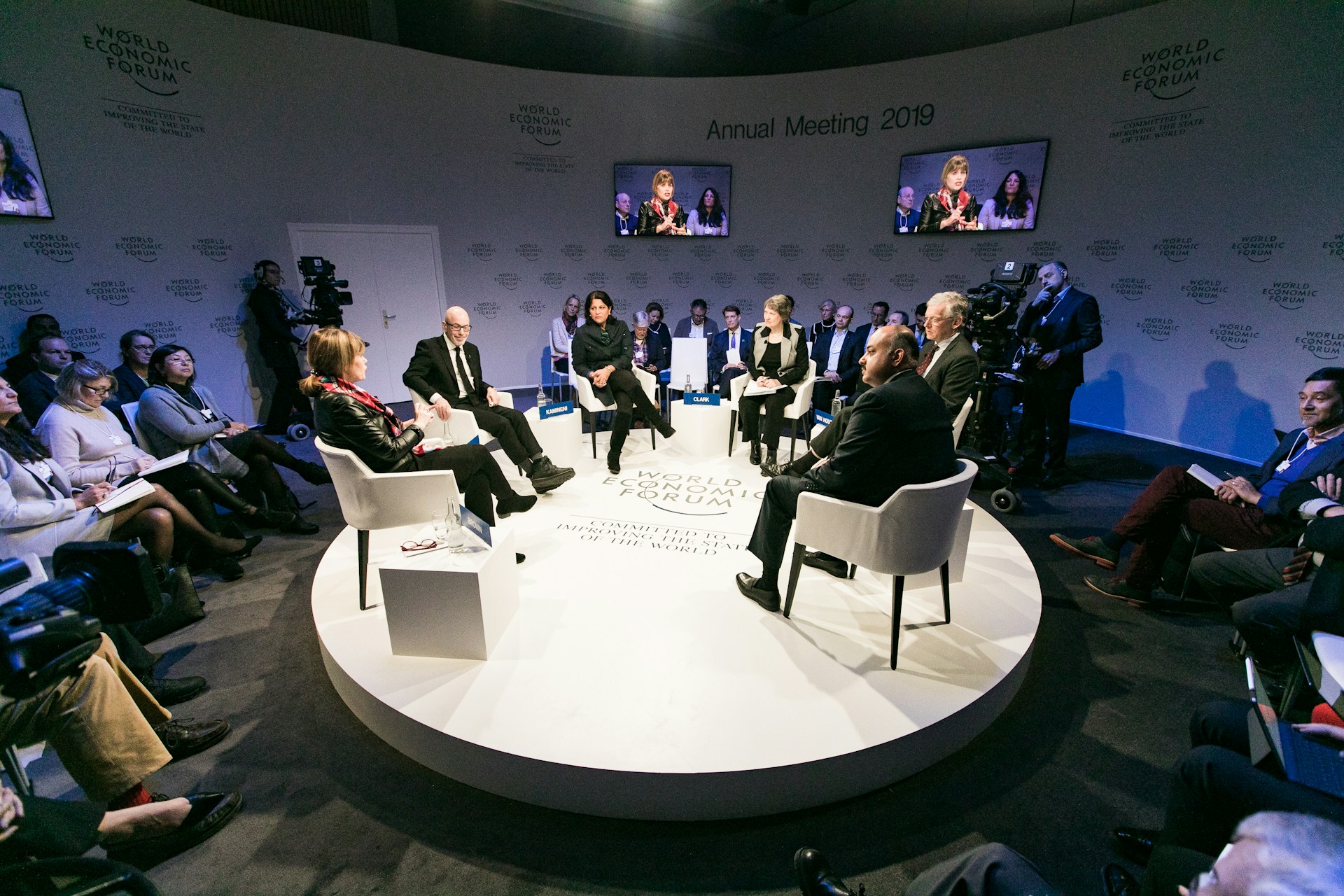 Broadcasted panel discussion with cameras, lighting, and large screens showcasing a professional visual setup for a panel discussion