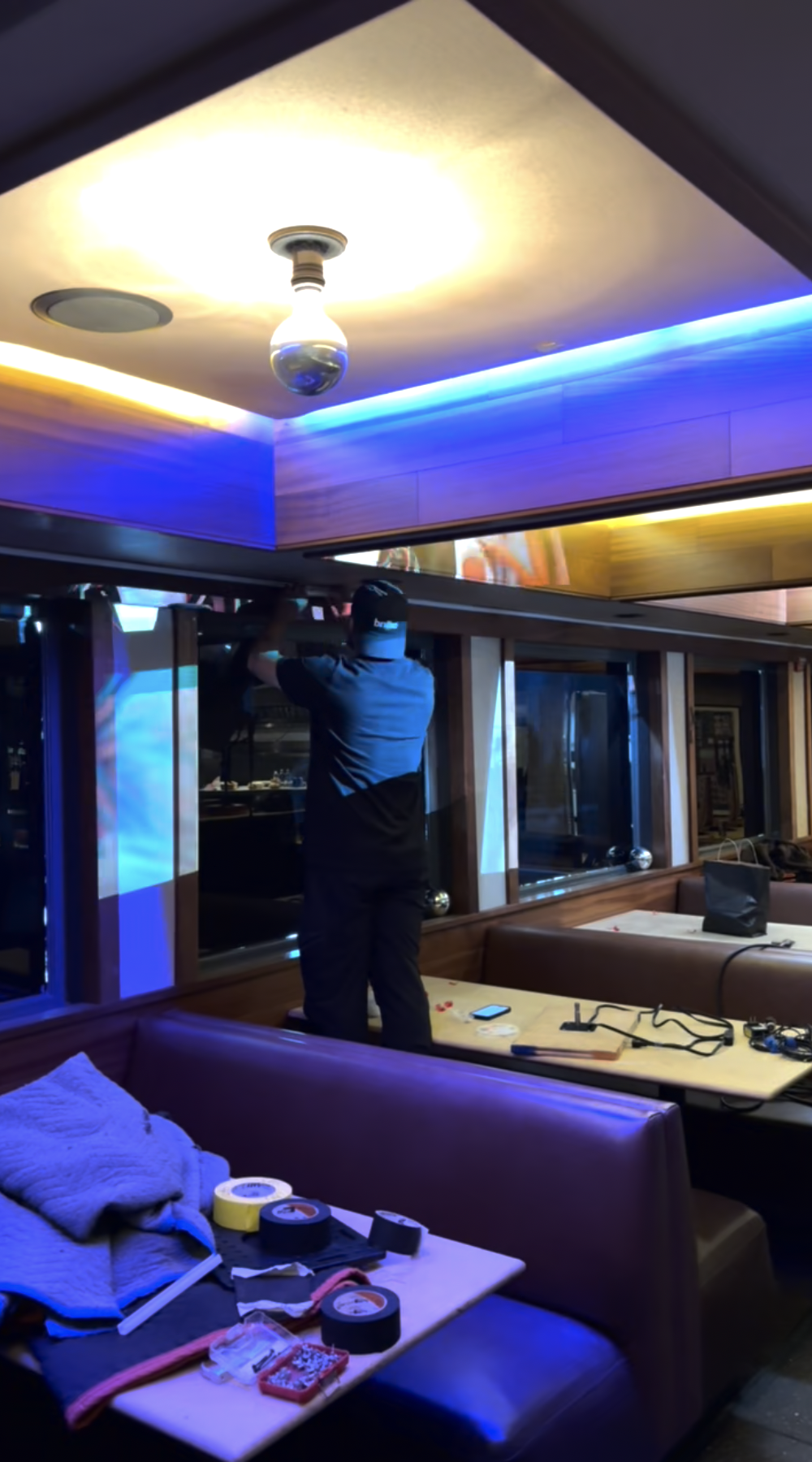 Technician installing scenic lighting and projection elements inside a branded corporate event space as part of scenic design for a San Francisco live event.