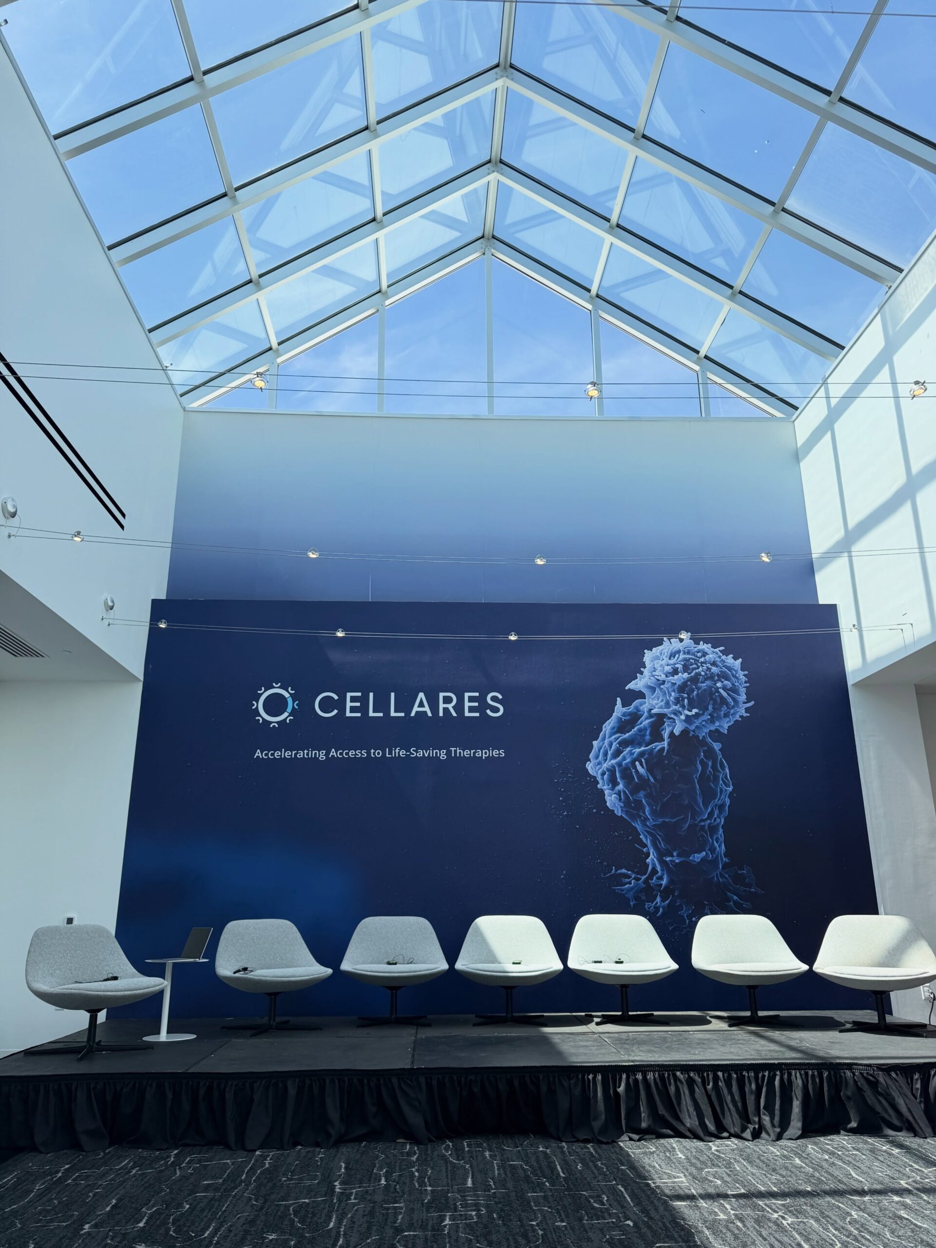 A Cellares backdrop behind five chairs set for a panel, on black skirted staging