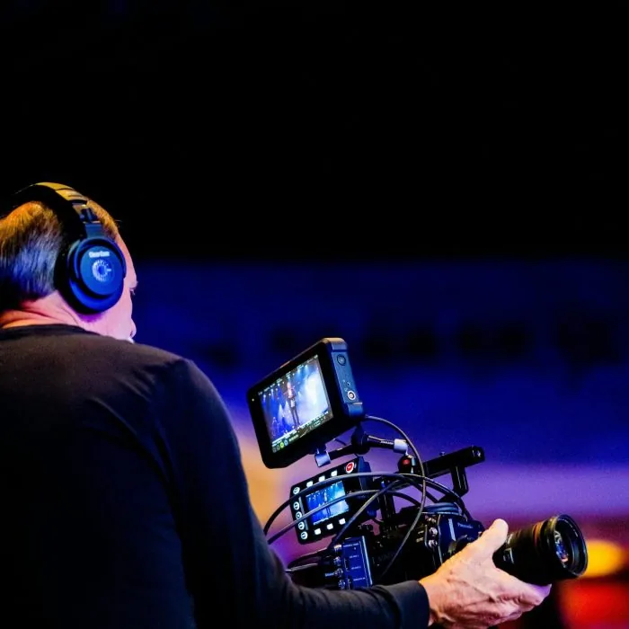 A man wearing headphones and holding a camera, capturing high-quality footage for audio visual production services in San Francisco.