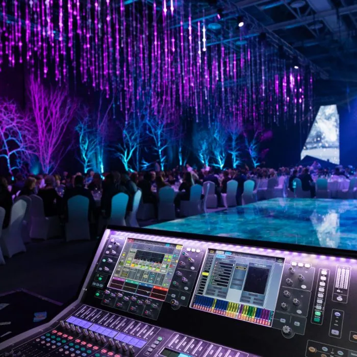 A stage with lighting set up in a large room, featuring a presentation and a group of people, supported by audio visual production services.